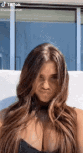 a woman with long hair and a very large breast is sitting on a couch .
