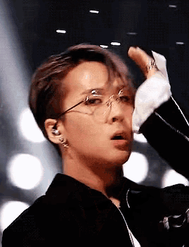 a close up of a person wearing glasses and a jacket on a stage .