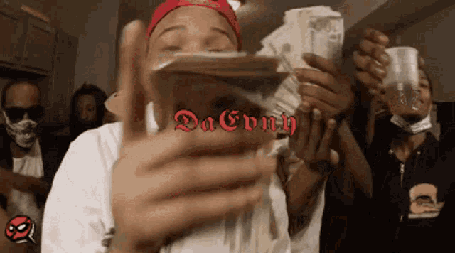 a man in a red hat is holding a stack of money in front of his face with the words da every on the bottom right