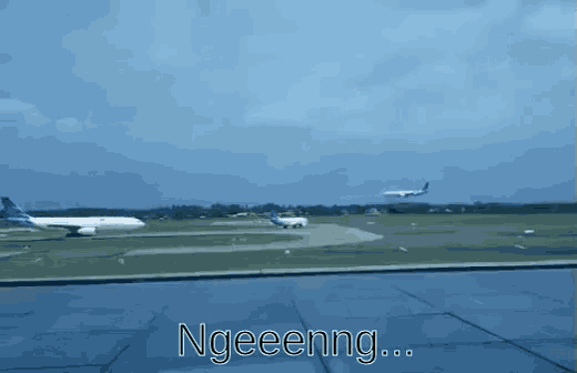 a plane is taking off from an airport runway and the words ngeeenng are visible