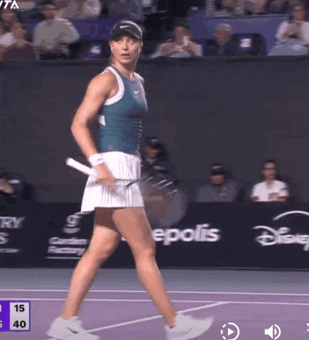a woman is playing tennis on a court with a disney advertisement behind her