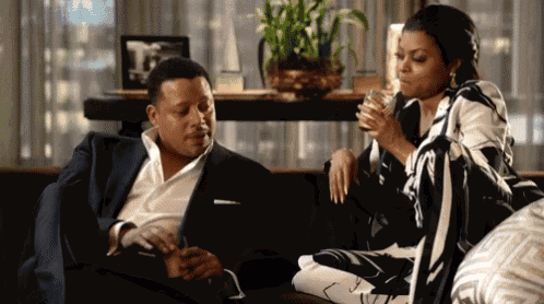 a man and a woman are sitting on a couch with a drink in their hands .
