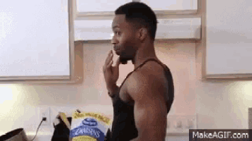 a man is standing in a kitchen eating a bag of potato chips .