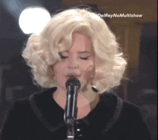 a woman with blonde hair singing into a microphone with the words delreynomultishow on the bottom