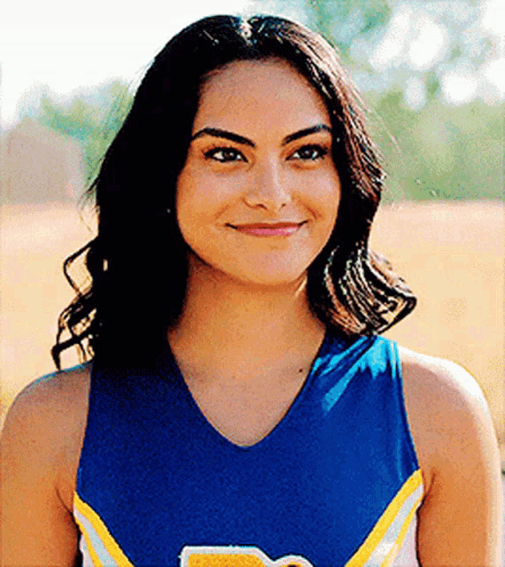 a close up of a cheerleader wearing a blue and yellow uniform and smiling .