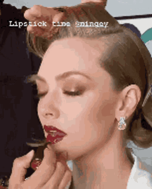 a woman is getting lipstick applied to her lips .