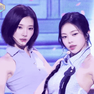 two women are standing next to each other on a stage with a microphone in their mouths