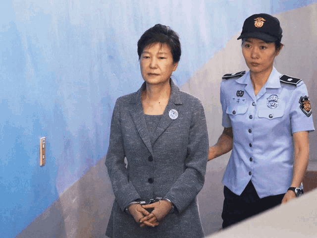 a woman in handcuffs is being escorted by a woman in a police uniform