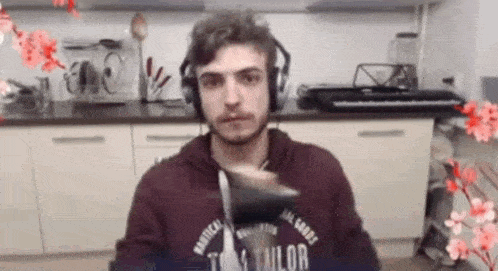 a man wearing headphones is sitting in a kitchen with a keyboard .
