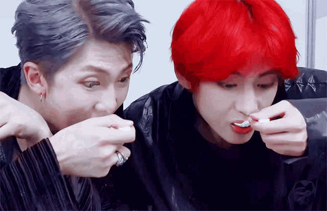 a man with red hair and a man with gray hair are eating something together