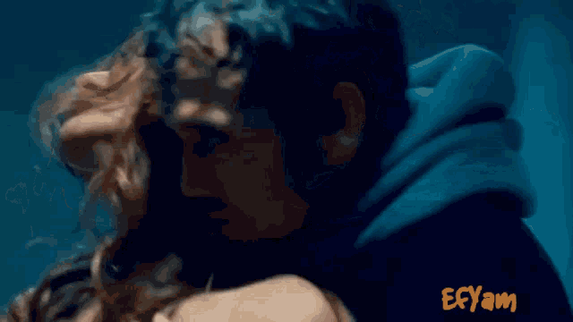a man and a woman are kissing in front of a sign that says efqam
