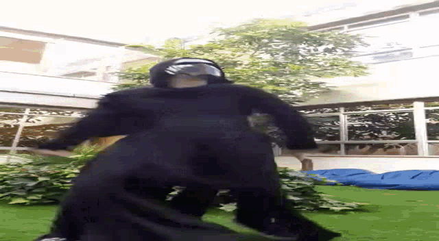 a person in a black costume is standing on stilts in a garden .