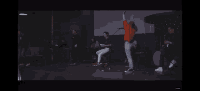 a group of people are dancing on a stage with their arms outstretched .