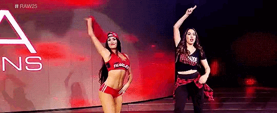two women are standing next to each other on a stage and dancing .