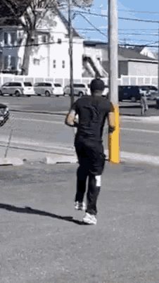 a man in a black shirt and black pants is running down the street .