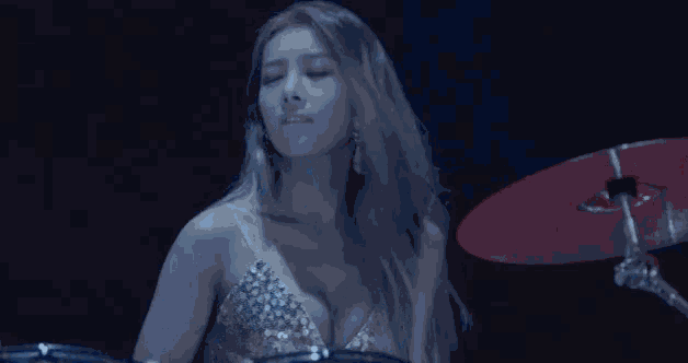 a woman is playing drums in a dark room