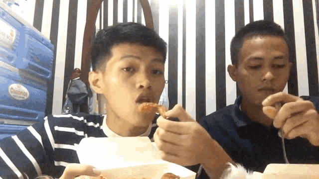 two boys are eating food in front of a blue container that says ' california ' on it