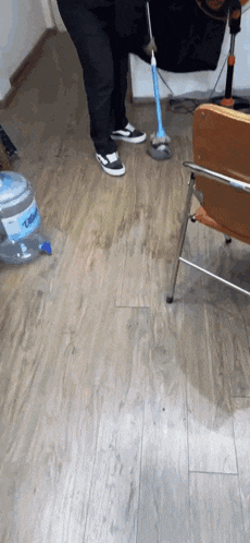 a person is cleaning the floor with a mop and a bottle of liquid water