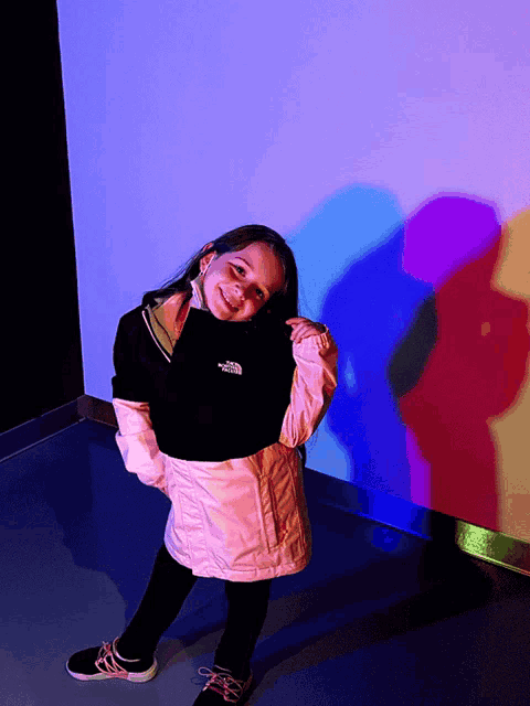 a little girl wearing a jacket that says the north face on it