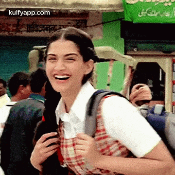 a woman with a backpack is laughing in a crowded street .