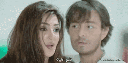 a man and a woman are looking at each other and the woman is saying something in arabic .