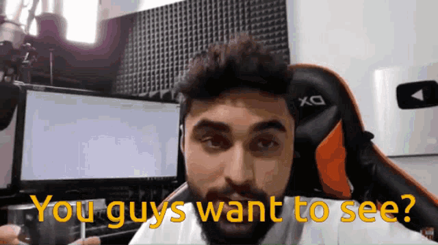 a man sitting in front of a computer with the words " you guys want to see " behind him