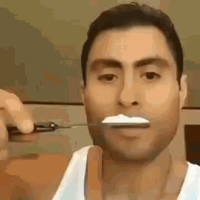 a man is brushing his teeth with a toothbrush and a knife .