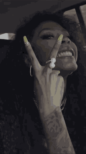 a woman with a tattoo on her arm is making a peace sign with her hands