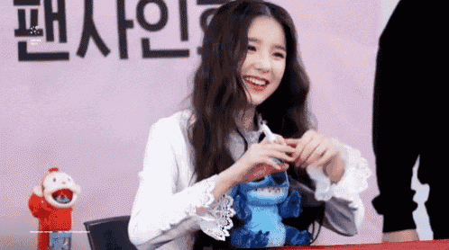 a woman is sitting at a table with a stuffed animal in her hands .