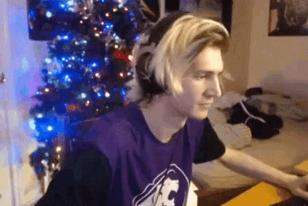 a man wearing headphones is sitting in front of a christmas tree in a room .