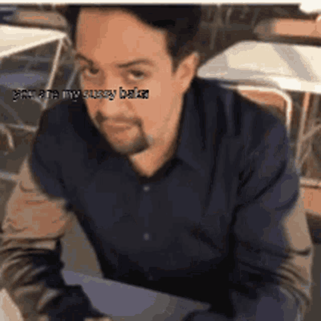a man in a blue shirt is sitting at a table with a caption that says " i 'm in my pussy bitch "