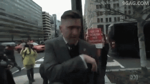 a man in a suit and tie is holding a sign that says justice for socialism over capitalism