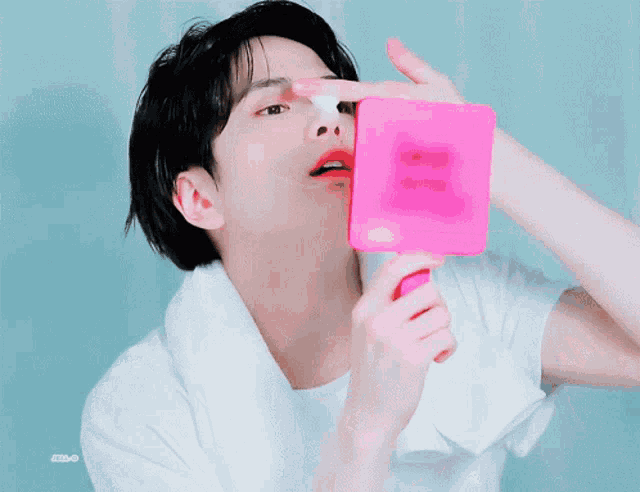 a man is looking at his face in a pink mirror with a sticker that says ' a ' on it