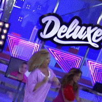 a woman in a pink shirt is dancing in front of a deluxe sign