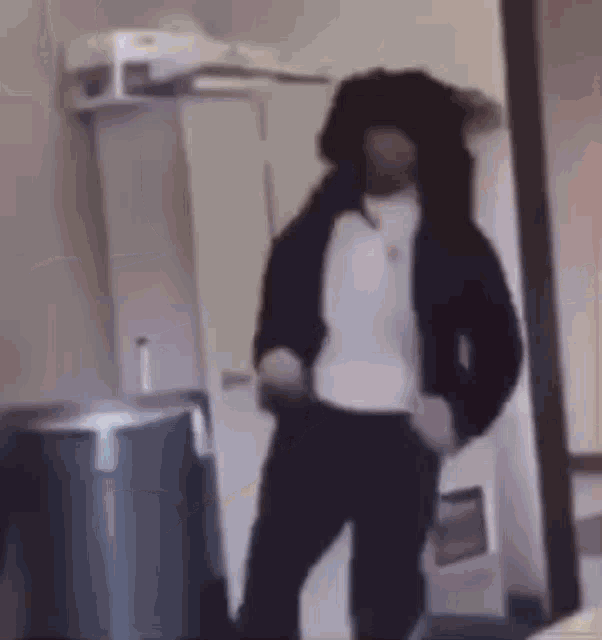 a man with dreadlocks is standing in a room with a trash can .
