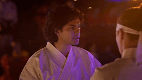 a man in a white karate uniform stands in front of a woman