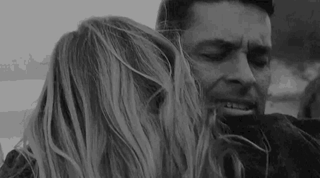 a man is hugging a woman in a black and white photo .
