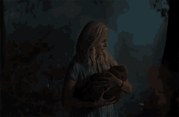a woman holding a baby in her arms in a dark room
