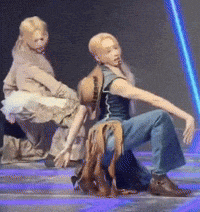 a man and a woman are dancing on a stage with a blue light behind them
