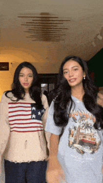 two women standing next to each other one wearing an american flag sweater and the other wearing a blue t-shirt