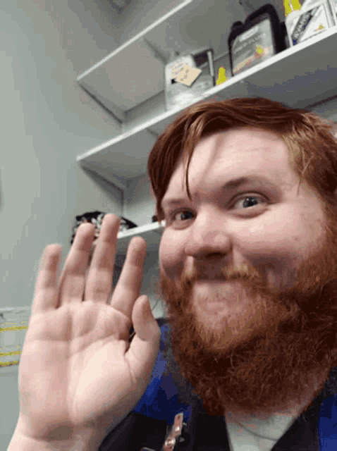 a man with a beard is giving a high five in front of a shelf with a bottle of kleenex on it