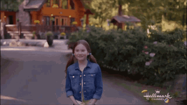 a girl in a denim jacket is standing in front of a house with the hallmark channel logo on the bottom