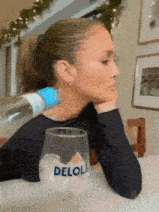 a woman is sitting at a table with a deloli wine glass