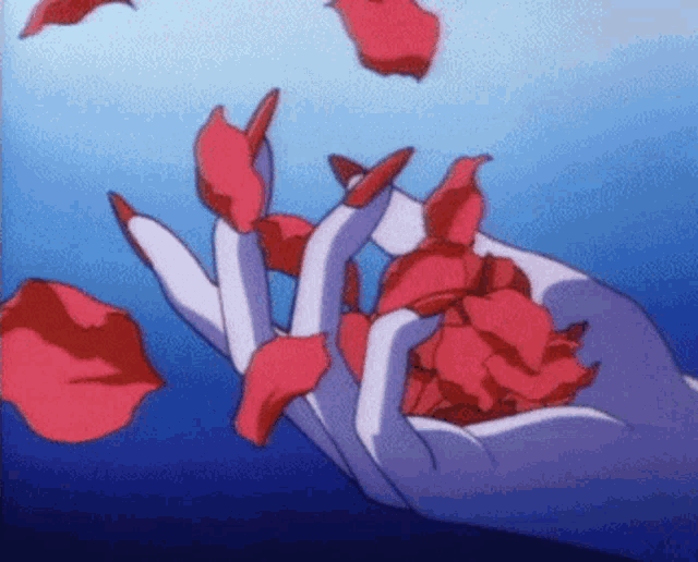 a hand with long red nails is holding a bunch of red rose petals .