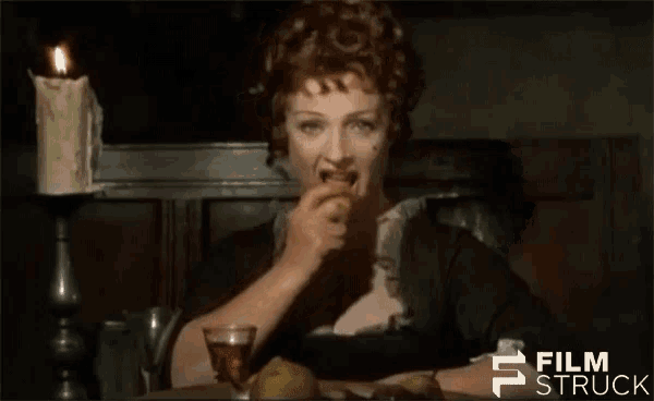 a woman is sitting at a table with a glass of wine and a candle in the background with the words film struck visible