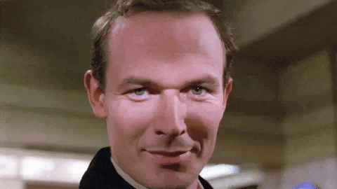a close up of a man 's face with a bald head and blue eyes .