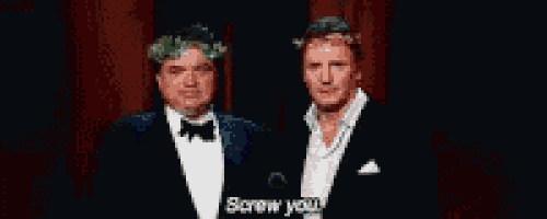 two men in tuxedos are standing next to each other and one of them says " screw you "