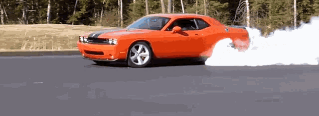 an orange car is doing a burnout on the road