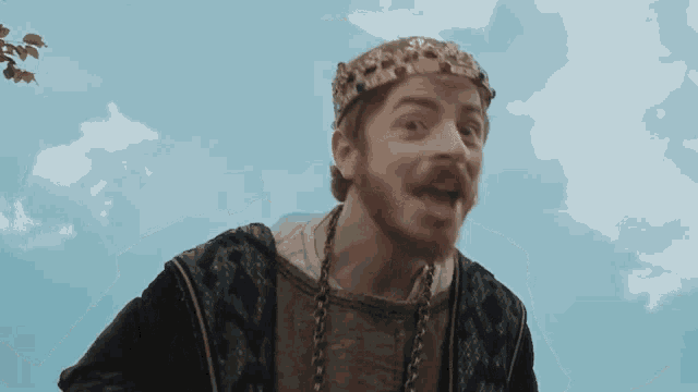 a man with a beard wearing a crown and a necklace