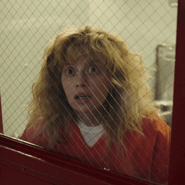a woman in a jail cell behind a glass fence